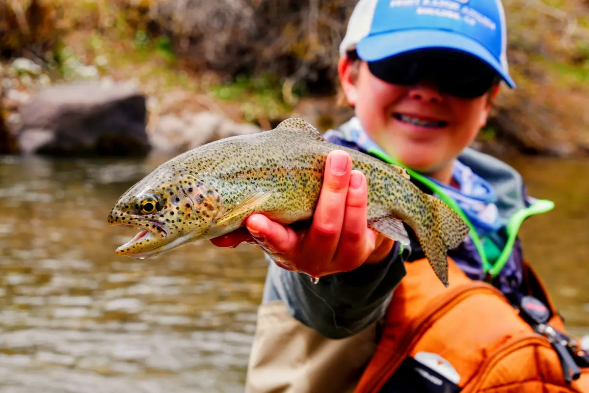 Happy first-time angler with a beautiful rainbow trout caught on the Bow River