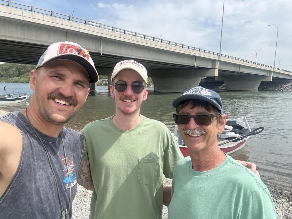 Dan King, King Trout Outfitters guide, with clients at a Bow River access point after a day of guided fishing, drift boats and a Calgary bridge in the background